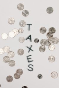 Scattered coins around the word 'TAXES', symbolizing personal finance and taxation.